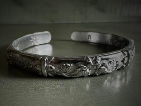 【瓦亘卡堤寺2567年人缘鸟法镯】 无禁忌冠兰吉祥物，随心佩戴，福运常伴！ 法镯中间图腾是双灵鸟窃窃私语，缔结善缘，开启贵人磁场；周身刻古老符文，汇聚人缘、财运与好运，助力人际和谐、事业顺遂、内侧藏有寺庙防伪印记，正宗加持，诚心可鉴。飞机铁材质轻盈坚韧，贴身如羽，低调而神圣。